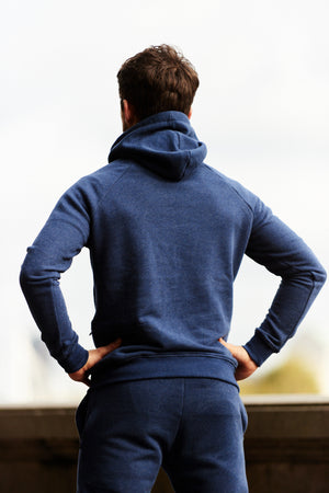 back view photo of a man posing while wearing a navy sole ambition training hoodie with zip pockets