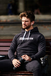 Man sitting on park bench listening to music wearing a Sole Ambition black workout hoodie with zipper pockets