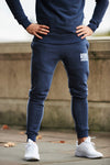 Stylish athlete wearing pair of men's navy blue slim fit gym bottoms with zip pockets from Sole Ambition on London streets