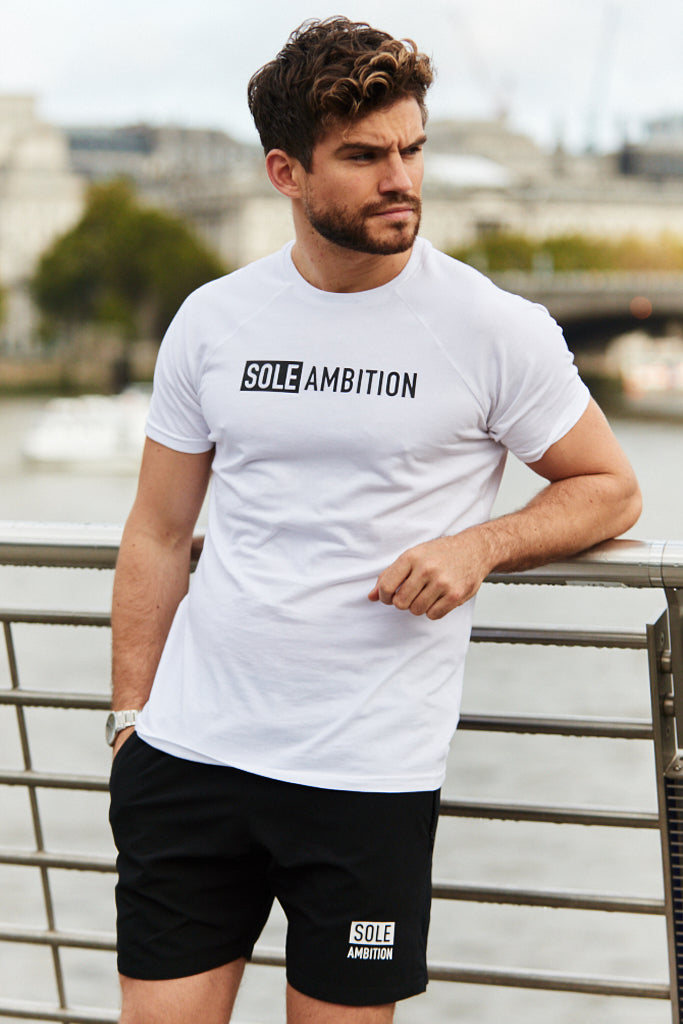 Man posing on london bridge with a river background in a Sole Ambition white slim fit gym t-shirt, made from organic combed cotton and elastane