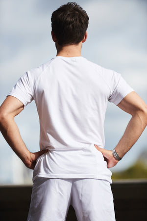 A back view of a man posing with a muscle fit white gym top on from Sole Ambition