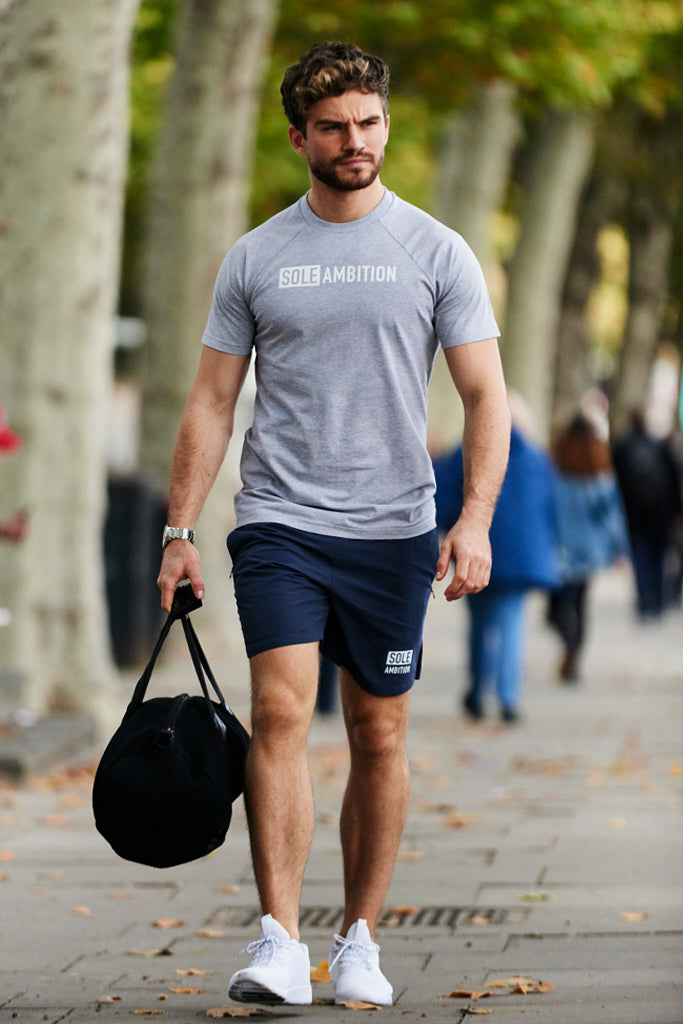 Man walking to the gym with a sole ambition navy shorts and grey workout t shirt combo