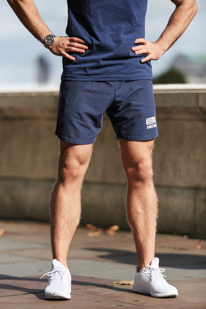 Front close up shot of a man wearing slim fit navy athletic gym shorts with zipper pockets from Sole Ambition