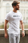 A side view of a man wearing a Sole Ambition skinny fit white workout t-shirt on the street