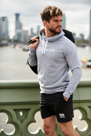 Man poses with bag over one shoulder while wearing a grey muscle fit printed gym hoodie with thick cotton material