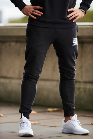 Young athlete in a pair of skinny fit mens black gym joggers with zip pockets and white brand print from Sole Ambition